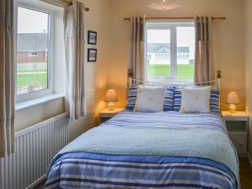 伯克顿Rosemarys Sea View的一间卧室配有蓝色的床和2个窗户