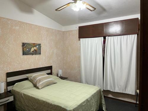 皮里亚波利斯Barrio Country的一间卧室配有一张带吊扇和窗户的床。