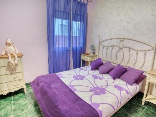 卡隆赫Casa Parc Aumell的一间卧室配有一张带紫色床单和紫色枕头的床