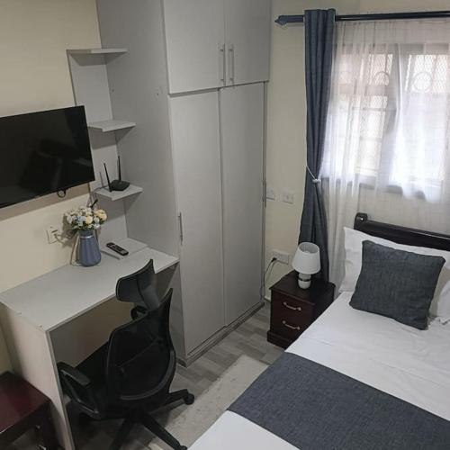 内罗毕Sharz place的一间卧室配有书桌和一张带电脑的床。