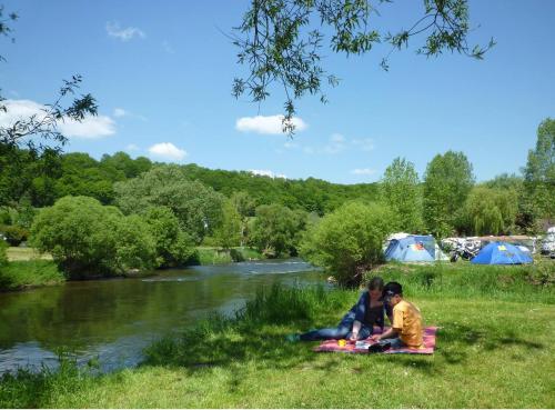 ReisdorfLeaf camping Reisdorf的两个人坐在一条河旁的毯子上