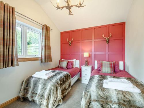 MinishantAppletree Lodge的红色墙壁客房的两张床