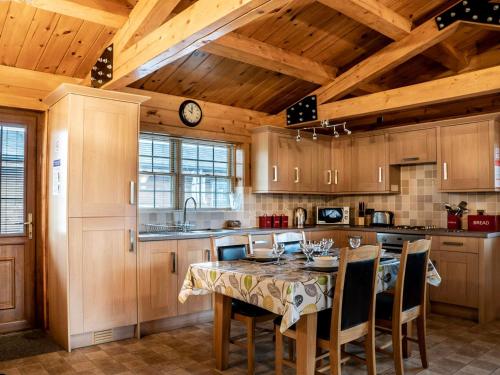 Leake Common Side湖景度假屋的厨房配有桌椅和木制天花板。