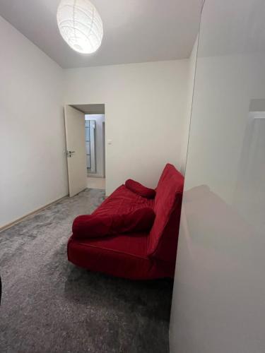 华沙Apartament Szczęśliwicka的一张红色沙发,坐在墙上的房间