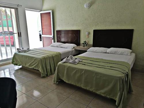 曼萨尼约Hotel Rio Balsas的配有窗户的酒店客房内的两张床