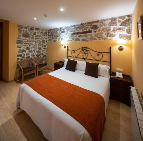 圣伊拉里奥-萨卡尔姆里波尔酒店的酒店客房设有一张大床和石墙