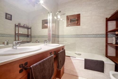 纳瓦塞拉达Chalet Navacerrada Piscina Privada的浴室配有2个盥洗盆、浴缸和浴缸。