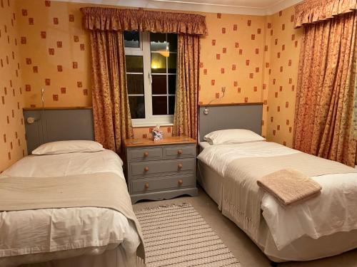 米尔登霍尔Silver Lodge Guest House的一间卧室设有两张床和窗户。