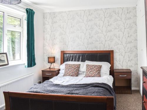坎特伯雷Bay House的一间卧室配有一张带白色墙壁和绿色窗帘的床