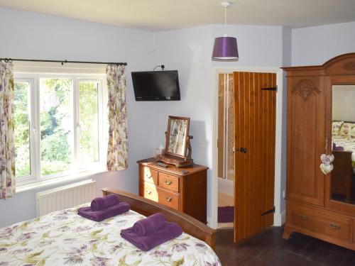 圣伦纳兹奥克迪恩度假屋的一间卧室配有一张带紫色枕头的床