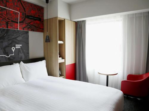 大阪大阪梅田宜必思酒店的酒店客房带白色的床和红色椅子