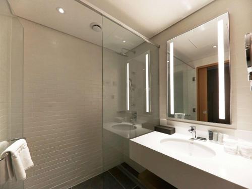 蔚山Mercure Ambassador Ulsan的一间带水槽和镜子的浴室