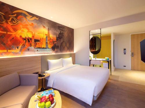 曼谷ibis Styles Bangkok Ratchada的酒店客房配有白色的床和沙发。