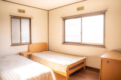 诹访市一組貸切宿 岡村 弐番館 一棟まるまる貸切的带两张床和两个窗户的房间
