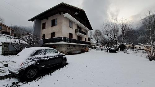 斯姿Tres bel appartement dans une maison avec SPA的停在雪覆盖的房子前面的汽车