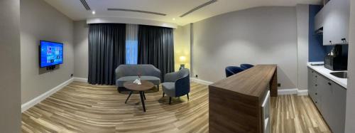 奥朱贝尔Warwick Al Jubail Hotel的客厅配有桌椅和电视。