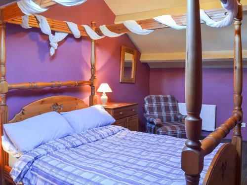 埃斯克代尔Birkerthwaite Barn-w41478的一间卧室设有一张天蓬床和紫色的墙壁