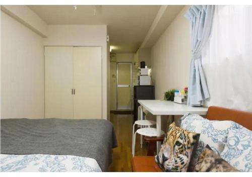 KugayamaPalace Mercy105 - Vacation STAY 11922的一间卧室配有一张床铺和一张桌子,还设有一间厨房
