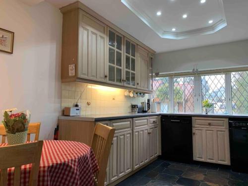 米尔福德昂西Crow’s Nest, Central New Forest coastal village beach apartment的厨房配有白色橱柜和带桌布的桌子