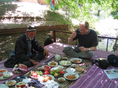 Yukary-UkhumHayat Guesthouse Nuratau Mountains的两个男人坐在野餐桌上,拿着食物盘