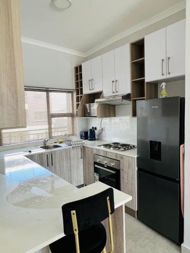 哈博罗内Zanaya Apartments的厨房配有黑色冰箱和桌子