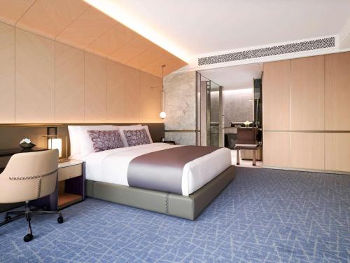 首尔Fairmont Ambassador Seoul的一间卧室配有一张大床、一张桌子和一张书桌