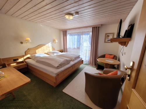 托特瑙Hotel Obergfell的卧室配有1张床、1张桌子和1把椅子