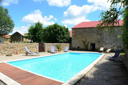 ChâteauponsacTwo Hoots - farmhouse with summer pool.的一座带椅子的庭院和一座建筑中的游泳池