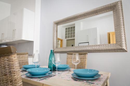 马拉加Apartments Holidays2Malaga City Center的一张桌子,上面放着蓝色的碗,玻璃杯和镜子
