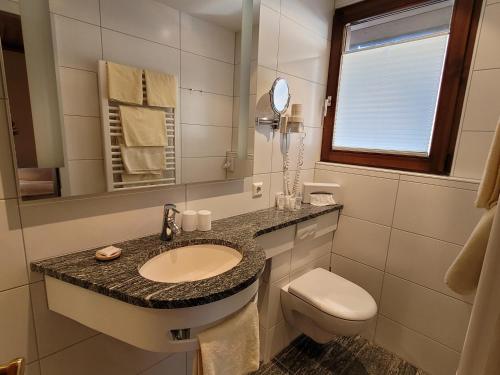 托特瑙Hotel Obergfell的一间带水槽、卫生间和镜子的浴室