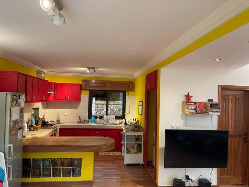 萨利波图尔Chambre diambar的厨房配有红色和黄色橱柜和平面电视。