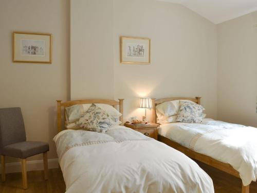 比灵斯赫斯特Woodlands Dairy Cottage的一间卧室配有两张床、椅子和一盏灯。