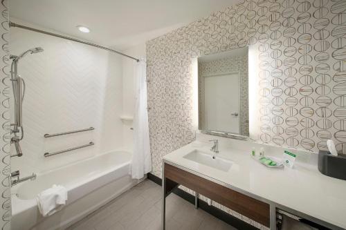 迪凯特Holiday Inn & Suites Decatur-Forsyth, an IHG Hotel的带浴缸、水槽和镜子的浴室