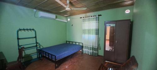 贾夫纳Aache Veedu Farm House的绿墙客房内的一张床位