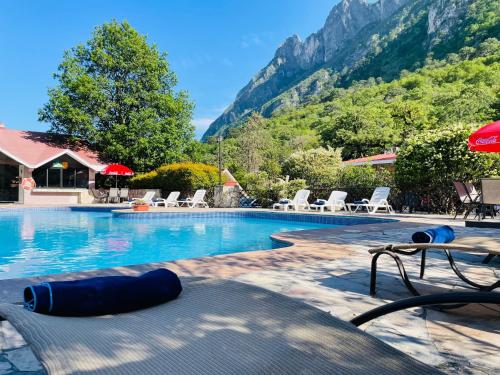 蒙特雷Hotel Chipinque的一个带椅子的游泳池,背景是山脉