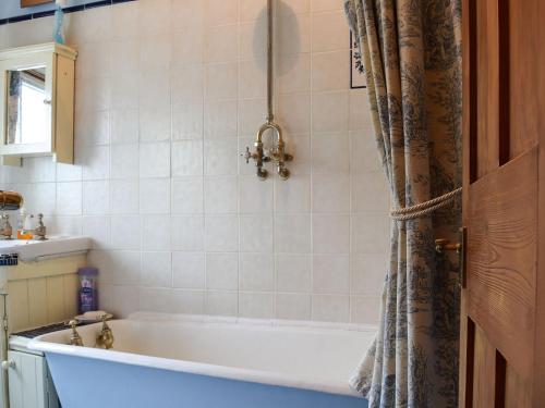阿什比圣勒杰斯Rebeccas Cottage的带浴缸和淋浴帘的浴室