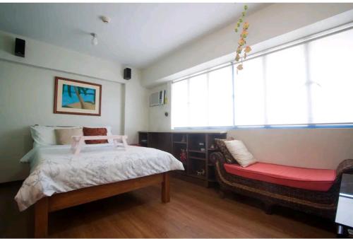 马尼拉WestParc Cedar Alabang的一间卧室配有一张床和一张红色长凳