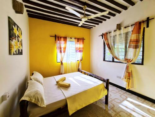 南威Frangipani House Nungwi Zanzibar的一间卧室设有一张黄色墙壁和窗户的床
