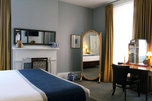 匹兹堡普里奥里酒店的一间卧室配有一张床、一张书桌和一面镜子