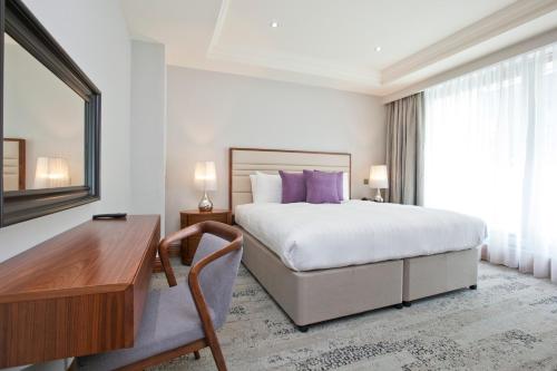 伦敦Sanctum Maida Vale的酒店客房配有一张床、一张书桌和一张书桌。
