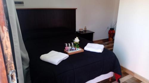 菲安巴拉Complejo San Antonio的配有黑色床、白色毛巾和瓶子的客房