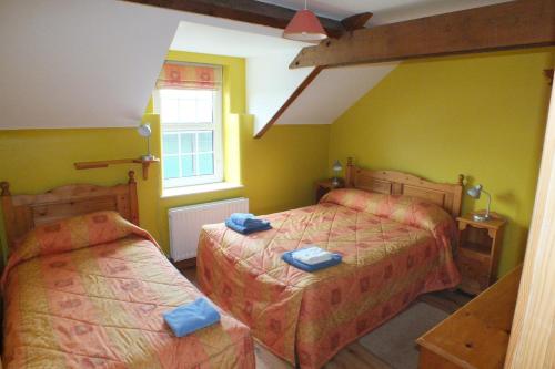 GreyabbeyBarnwell Farm Cottages Corn cottage的一间卧室设有两张床和窗户。