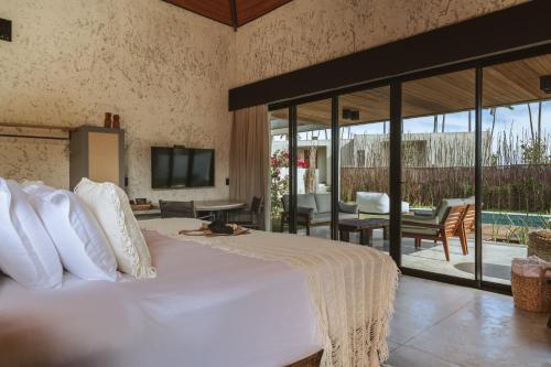 Passo de CamarajibeTuju Boutique Hotel的卧室设有一张白色大床和一个庭院。