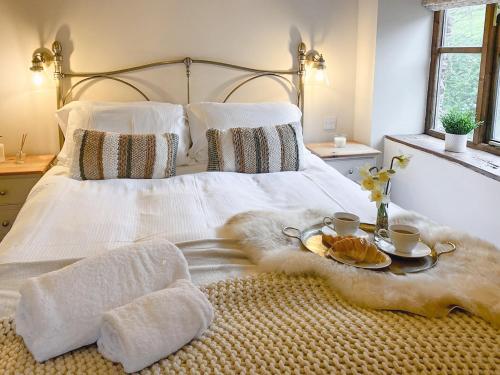 佩恩顿庞德之家乡村别墅的一张带白色毯子和两个杯子的床和一盘食物