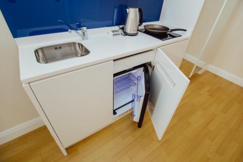 巴统ORBI GROUP APART-HOTEL的白色的厨房配有水槽和冰箱