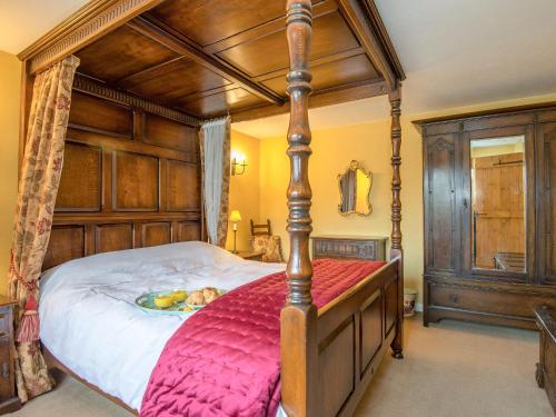 South WillinghamThe Thatch的一间卧室配有一张大天蓬床和红色毯子