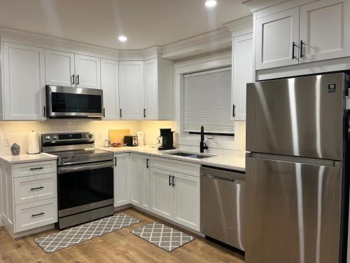 夏洛特顿City Modern Apartment的厨房配有白色橱柜和不锈钢冰箱