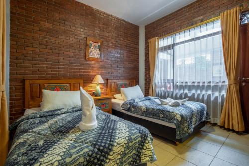 万隆Sekararum Butik Syariah Guesthouse的一间卧室设有两张床和砖墙