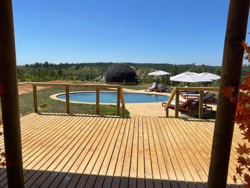 CatilloDOMO Y SPA INFINITO的一个带游泳池和遮阳伞的木制甲板