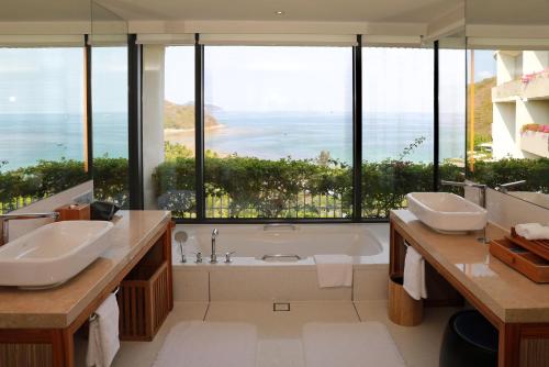 三亚三亚半山半岛洲际度假酒店(夏湾阳光浴场)的一间带两个盥洗盆和浴缸的浴室以及大窗户。